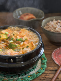 Hot boiling doenjang jjigae in a stone pot is a served with rice and kimchi
