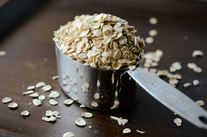 Rolled oats are piled up in a measuring cup.
