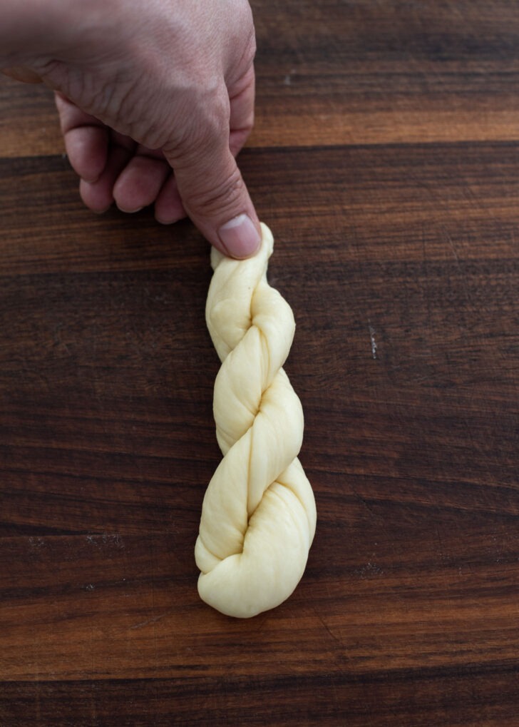 The ends of twisted dough is pinched by thumb to secure.