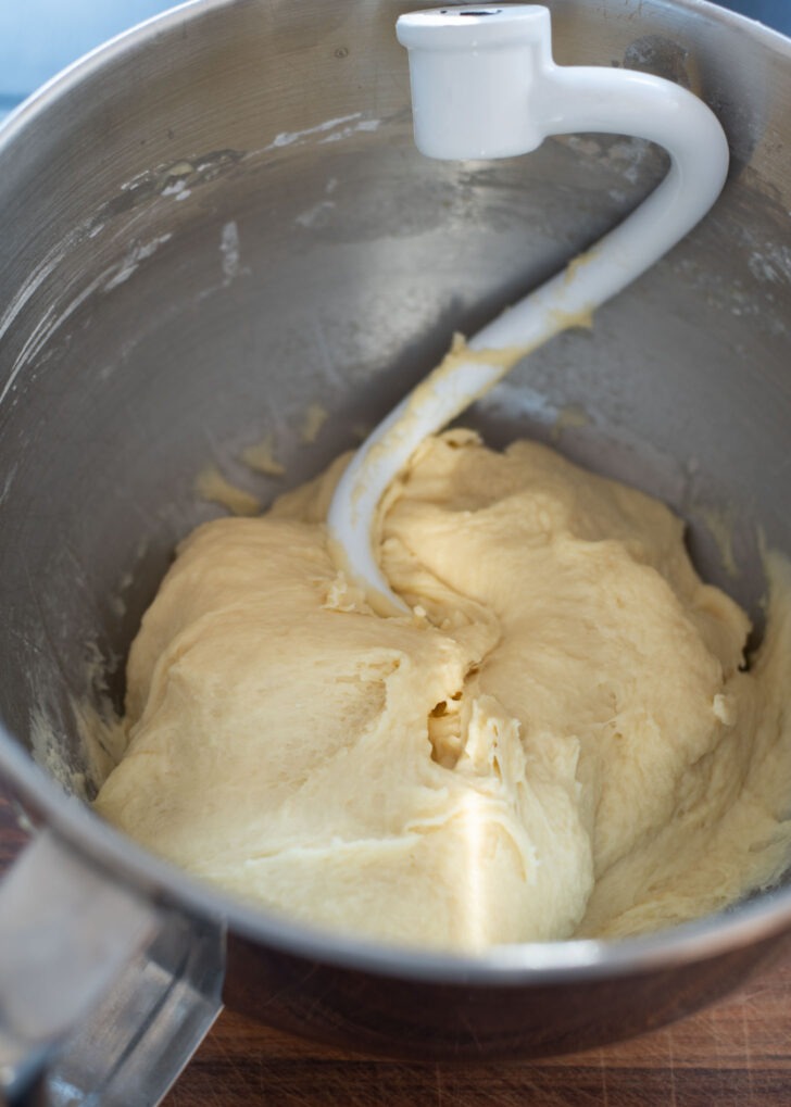 A dough hook in a electric mixer does a kneading job to complete to make the dough.