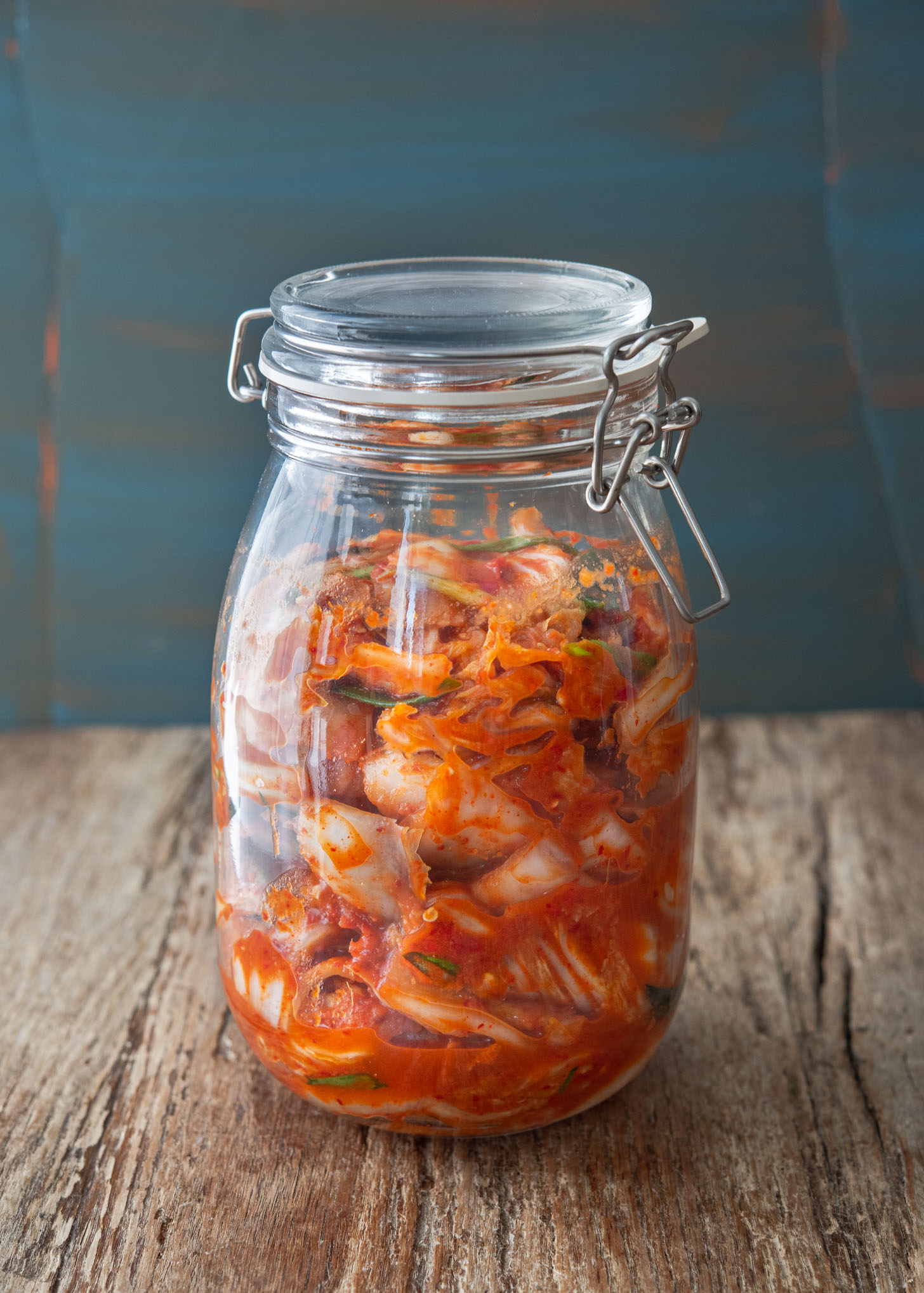 Vegan kimchi fermenting in a glass jar.