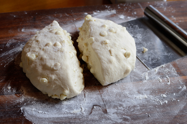 White chocolate chip bread dough is cut in half.